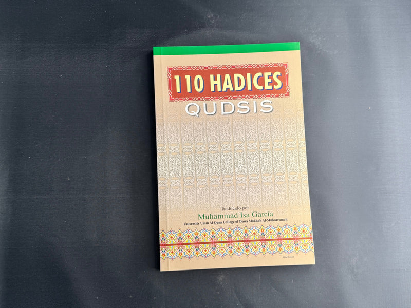 The book '110 Hadices' by Muhammad ibn al-Hasan, displayed flat on a dark gray surface. The cover is beige with a gold pattern, featuring a red title block and a green spine.