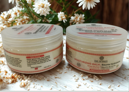 “Be Artisan Orange Blossom, Argan and Shea Butter moisturising balm in 150g jars, natural skincare displayed with white flowers on a textured surface.”